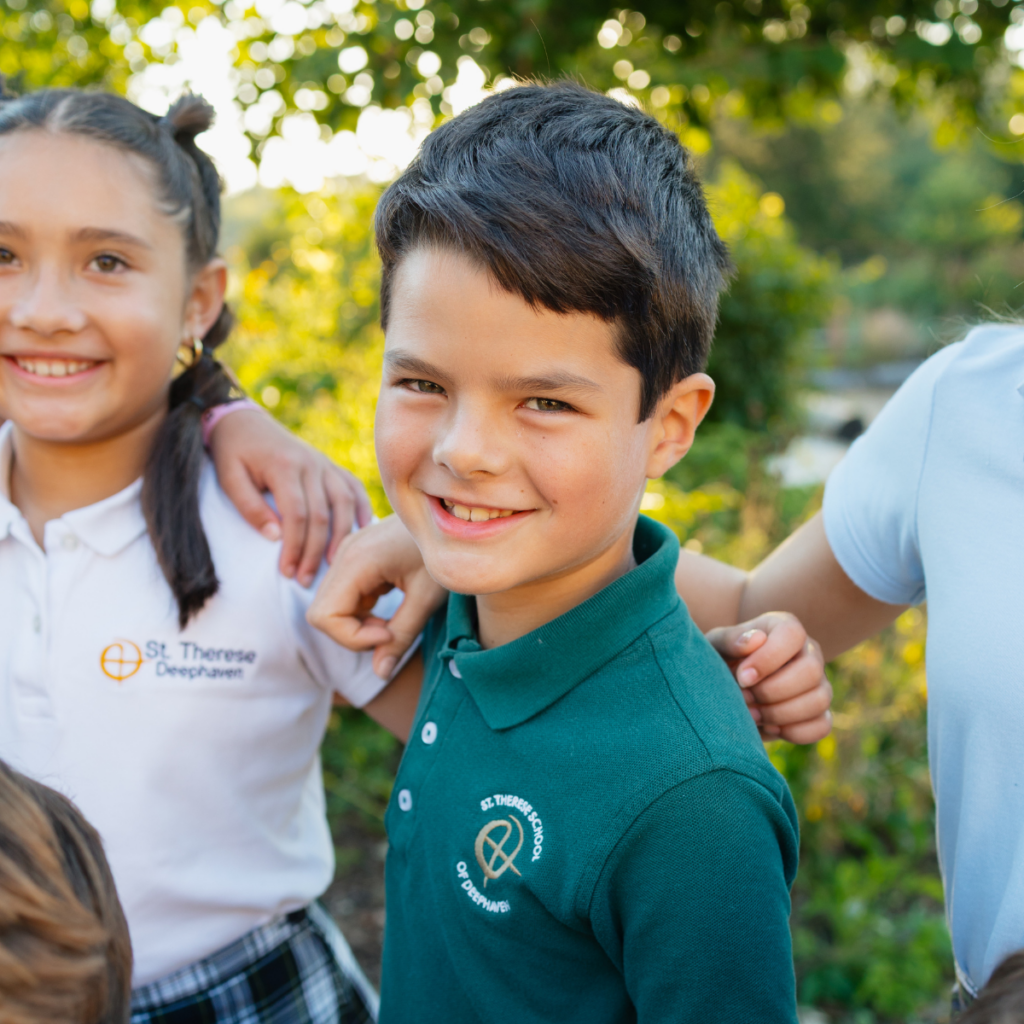 School children in uniforms smiling together outdoors in natural green setting
