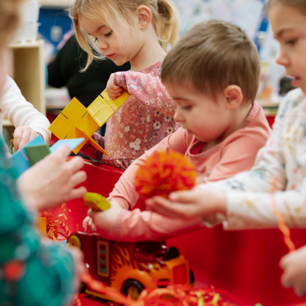 Young children engaged in hands-on sensory play with colorful toys and textures.