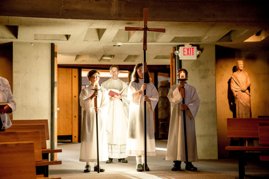 Religious procession with clergy in white robes carrying a large wooden cross