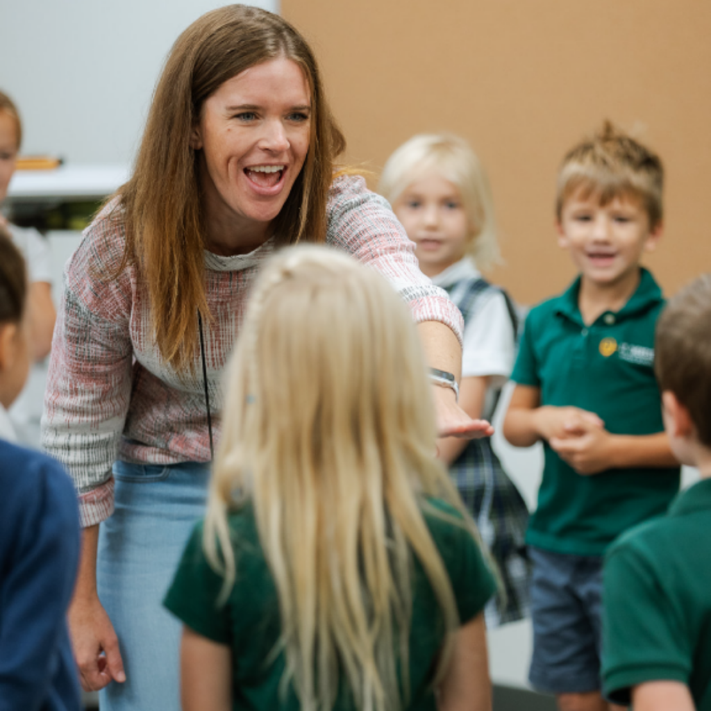 Teacher enthusiastically engaging with elementary school students in classroom setting.